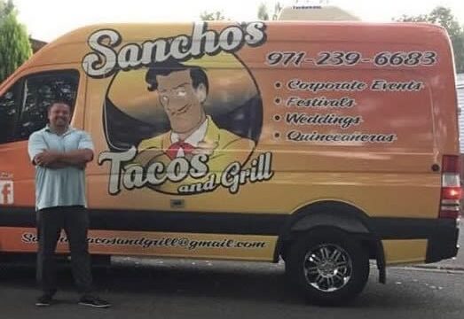 Santiago of Sancho's Tacos and Grill standing in front of the Sancho's van